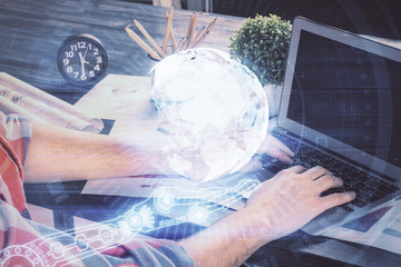 Double exposure of world map hologram with man working on computer on background. Concept of worldwideweb.