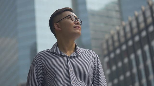 Portrait handsome businessman standing looking around urban city. Slow motion low angle shoot.