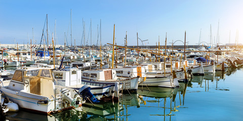 Private yachts and fishing boats moored at pier in seaport Blanes. Sailing and motor boats are moored at seawall. Vessels with catch of sea fish delicacies. Marina Blanes, Spain, Costa Brava