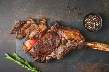 Top view of dry-aged marble beef steak Tomahawk on black slate with spices. Flat lay, dinner...