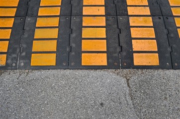 part of yellow-black  speed bump and part of asphalt