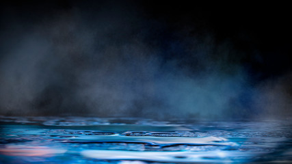 Empty dark scene with neon lights and smoke. Light neon spotlights, reflected on the wet asphalt, the surface is mirrored. Night view