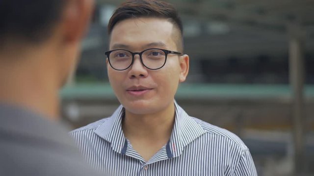 Close up portrait handsome asian businessman have conversation with employee standing on urban city. Slow motion shoot.