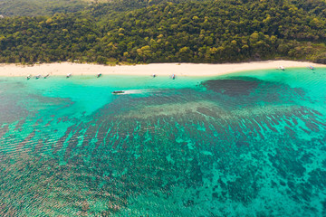 Puka Shell Beach, Boracay Island, Philippines, aerial view. Tropical white sand beach and beautiful lagoon. Tourist boats and people on the beach. People relax on the beautiful coast.