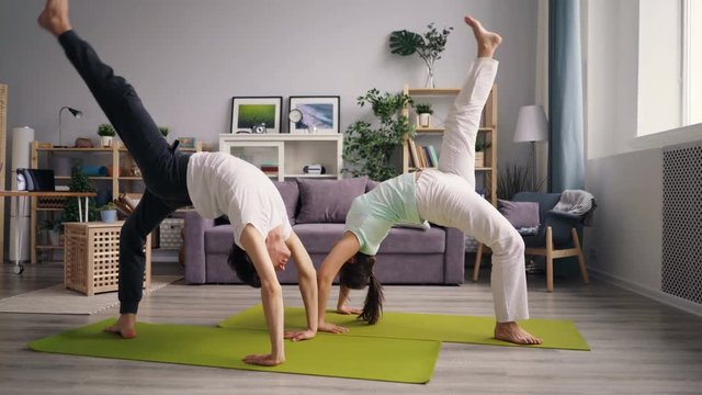 Husband and wife young people are doing sports at home practising crab position then relaxing on floor. Active lifestyle, relationship and leisure concept.