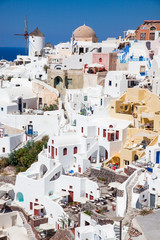 Fototapeta premium beautiful Oia town on Santorini island, Greece. Traditional white architecture and greek orthodox churches with blue domes over the Caldera, Aegean sea. Scenic travel background