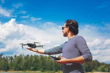 Young Man watching and navigating a flying drone in blue clear Sky