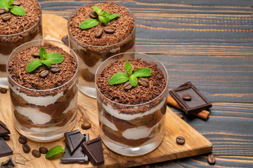 Classic tiramisu dessert in a glass on wooden background