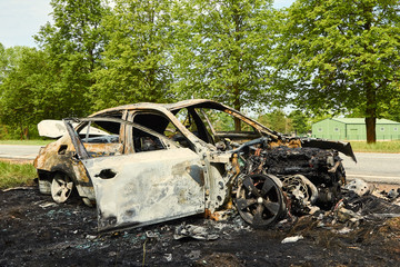 Fully burned car on roadside after collision with heavy truck