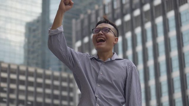 Portrait handsome asian businessman after a working have success and achievement standing looking around urban city. Slow motion low angle shoot.