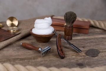 shaving accessories  - wooden razor with shaving brush and shaving foam on a rustic wooden...