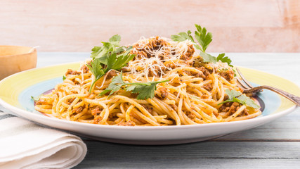 Portion of traditional Italian pasta on a plate close up - spaghetti bolognese with parmesan and parsley