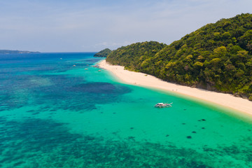 Fototapeta na wymiar Puka Shell Beach. Wide tropical beach with white sand. Beautiful white beach and azure water on Boracay island, Philippines, top view. Tourists relax on the beach.