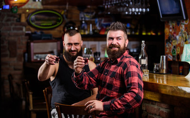 Men relaxing at bar. Friendship and leisure. Friday relaxation in bar. Friends relaxing in pub. Hipster brutal bearded man spend leisure with friend at bar counter. Order drinks at bar counter