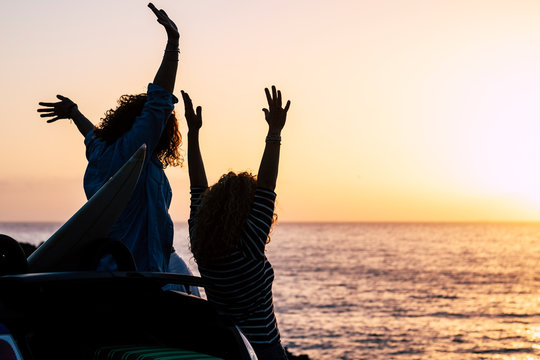 Happiness and successful concept with couple of women young friends enjoy the sunset on holiday summer vacation - joyful and people in outdoor travel leisure activity - ocean and sun background