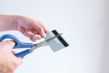 A woman cutting a credit card with scissors for stop making debt from it.