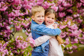 Romantic babies. Couple kids walk sakura tree garden. Tender love feelings. Little girl and boy. Romantic date. Spring time to fall in love. Kids in love pink cherry blossom. Love is in the air