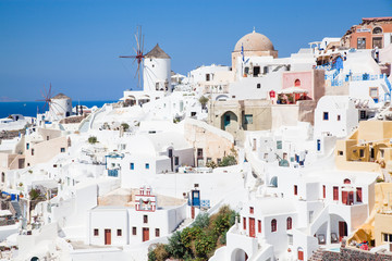 Fototapeta premium beautiful Oia town on Santorini island, Greece. Traditional white architecture and greek orthodox churches with blue domes over the Caldera, Aegean sea. Scenic travel background