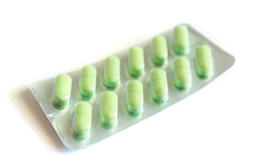 green medical pills in blister pack isolated on white background