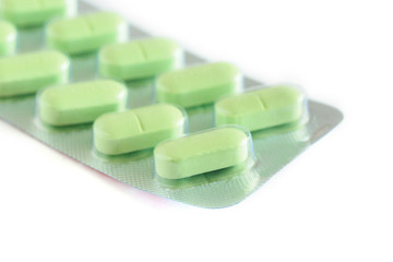 green medical pills in blister pack isolated on white background