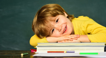 Back to school and happy time. Kid is learning in class on background of blackboard. Cheerful smiling child at the blackboard