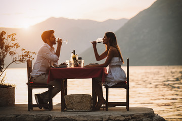 Couple is having a private event dinner on a tropical beach during sunset time - obrazy, fototapety, plakaty