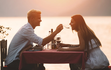People, vacation, love and romance concept. Young couple enjoying a romantic dinner on beach.