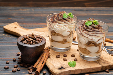 Classic tiramisu dessert in a glass on wooden background