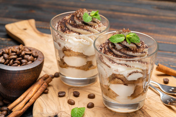 Classic tiramisu dessert in a glass on wooden background