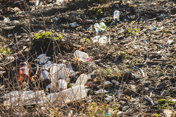 Ecological concept. Ecology problems of the planet Earth. Rubbish in places of rest by the sea. Plastic bottles among green grass and flowers.