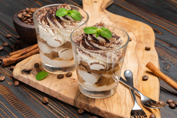 Classic tiramisu dessert in a glass on wooden background