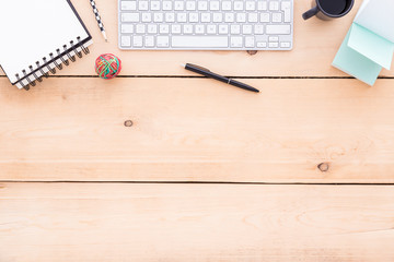 Wooden desk with coffee, keyboard and stationery.