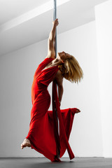 pole dance girl in red glamorous dress posing on a pole