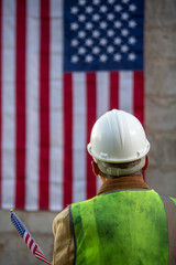 construction worker in hard hat on a concrete wall and american flag background
