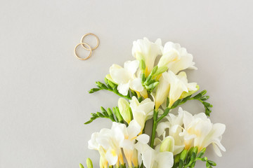 Wedding rings and beautiful freesia flowers on light background - obrazy, fototapety, plakaty