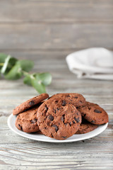 Plate with tasty chocolate cookies on wooden table
