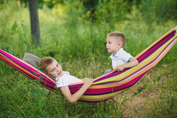 Two little boys sit in rainbow hammock