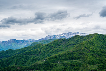 Montenegro, Snow covered high mountains and peaks near kolasin behind green tree covered mountains in unspoiled nature landscape