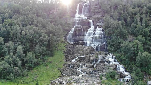 Spectacular waterfall among the rocks in the northern European forest taken by a slowly approaching drone. Scenic view of waterfall with crystal clear flowing water, nature and clean water going down