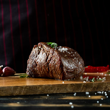 Cooking meat steak and adding salt and pepper on black copy space background for menu restaurant or recipe text.