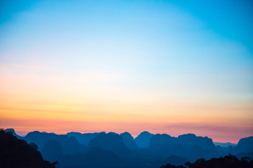 Fototapeta premium Landscape with beautiful dramatic sunset and silhouette of blue mountains at horizon, Thailand
