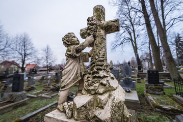 Obraz premium Grave on the cemetery in front of Virgin Mary old wooden church in Broumov town in Czech Republic