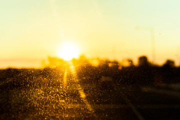 Golden sunshine beam glaring through dirty car windshield.