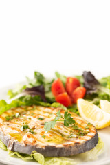 Grilled wordfish with salad and lemon on the white plate