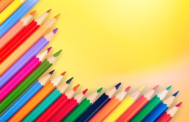 Many colored wooden pencils on yellow pastel background