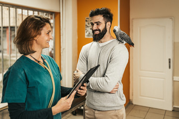 Young man with his African grey parrot at veterinary.