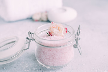 Spa and body care products. Aromatic rose bath Sea Salt, towel, candle on the grey background. Beauty skin care. Spa treatment