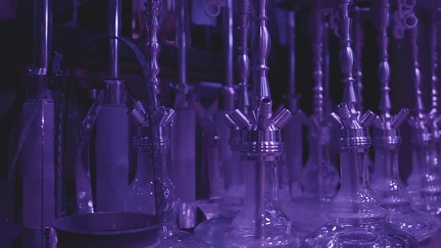 Hookahs are in a row in night club in blue light. Night lifestyle. Preparation for the party. Evening in the hookah
