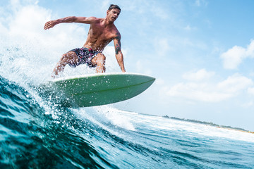 Young surfer with lean muscular body rides the tropical wave - obrazy, fototapety, plakaty