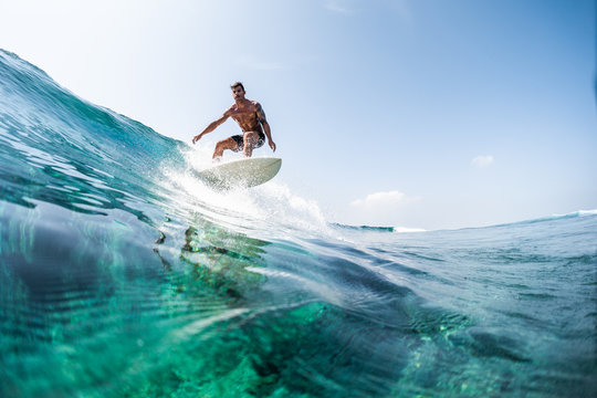 Young man surfs the glassy ocean wave at sunny day